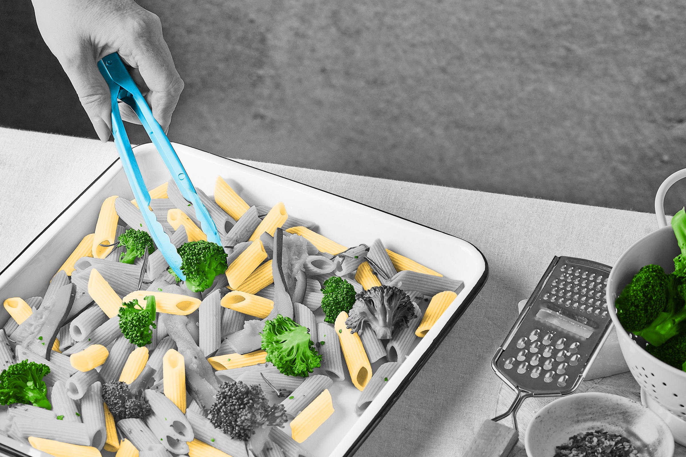 Person using tongs to prepare a tray full of pasta