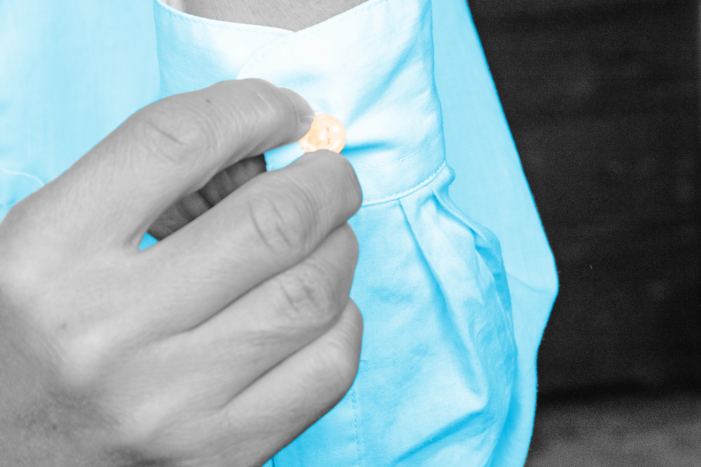Man's hand buttoning the collar of his shirt