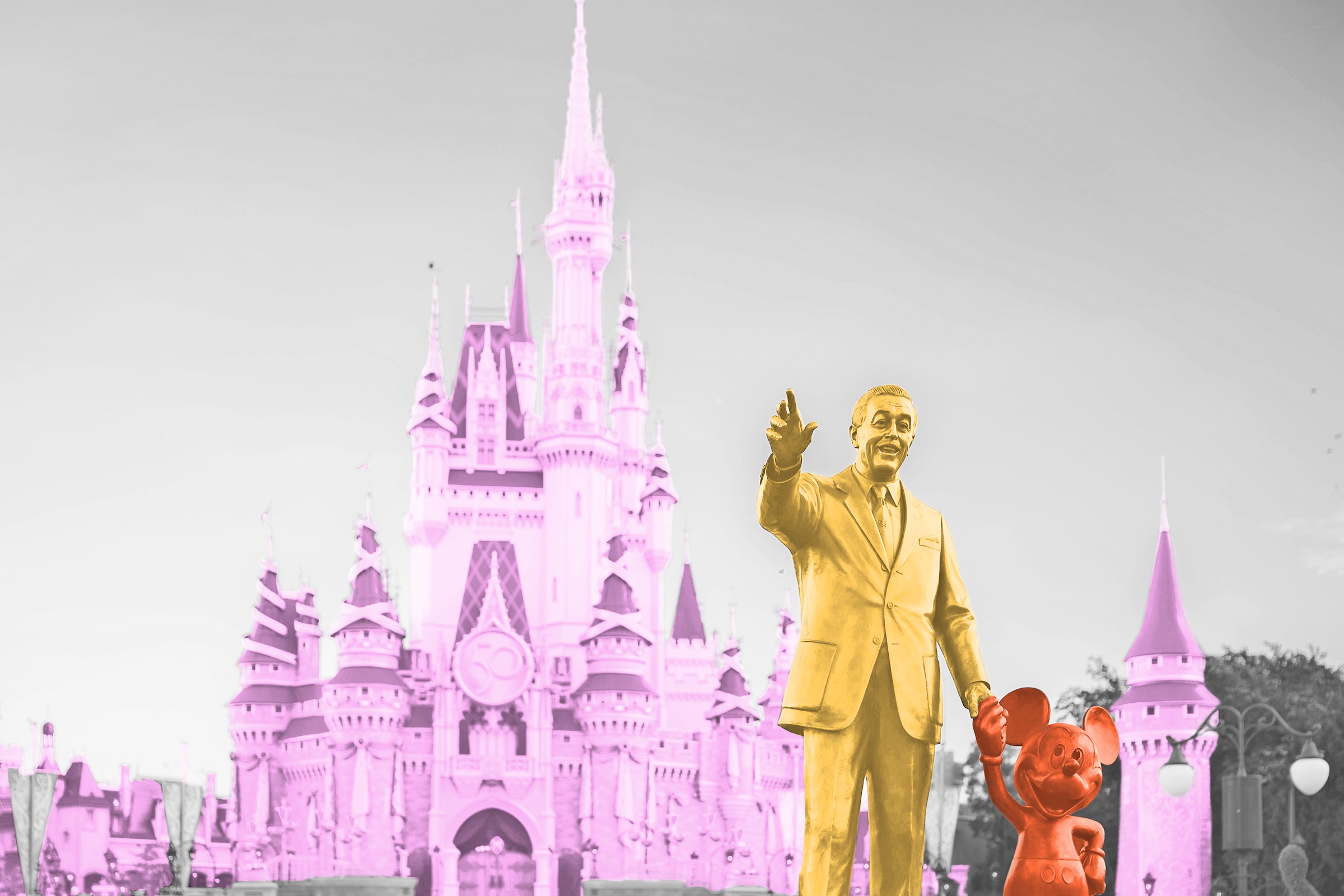 Statue of Walt Disney and Mickey Mouse in front of a Disney theme park castle