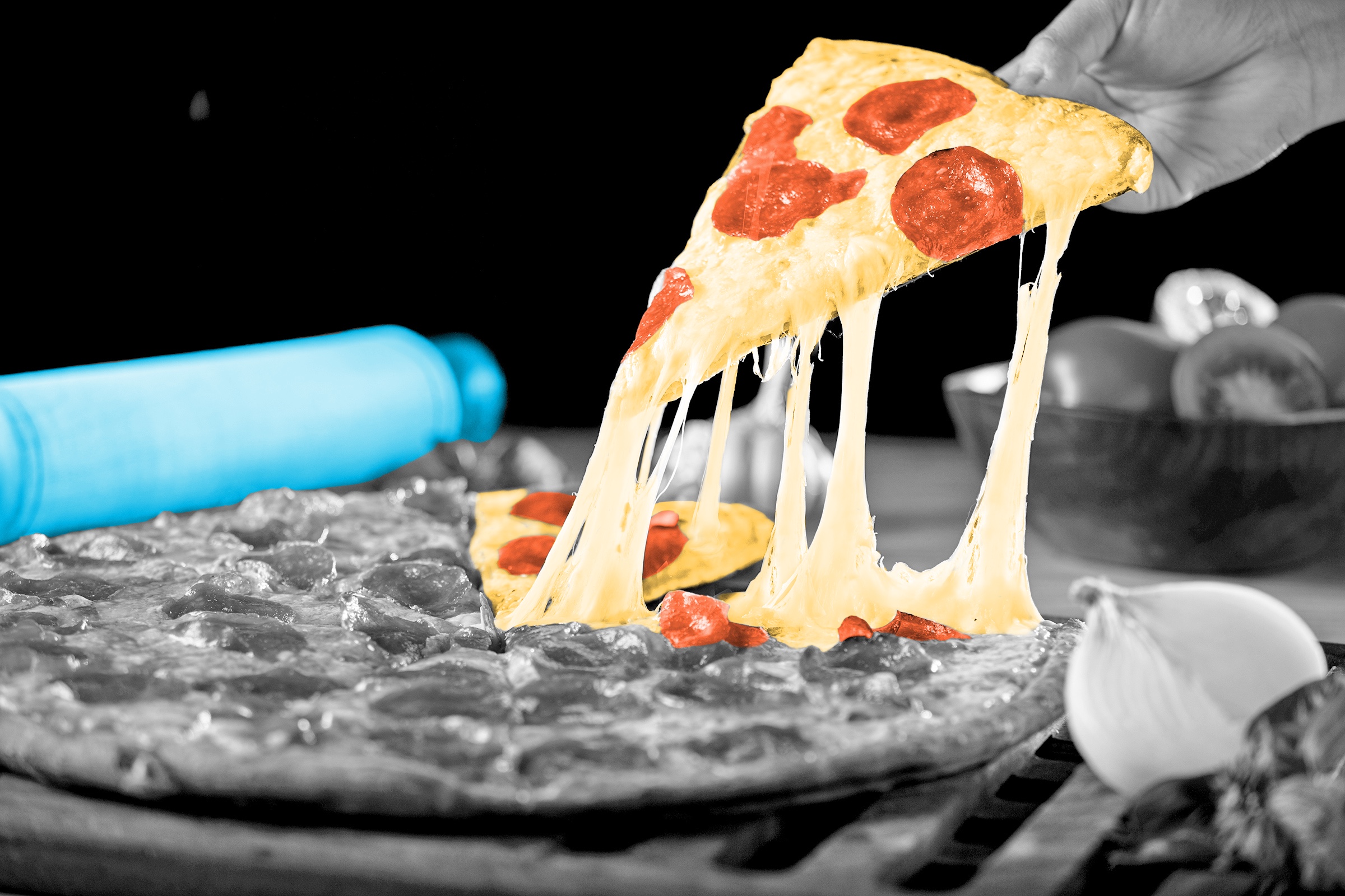 Cheese stretching from a slice of pizza as it's pulled from a pie