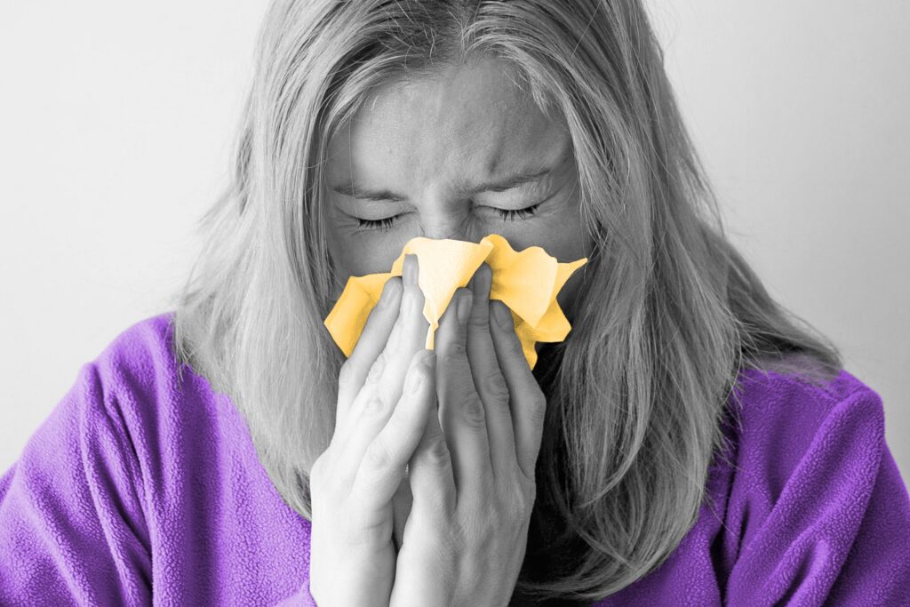 Woman sneezing into a tissue