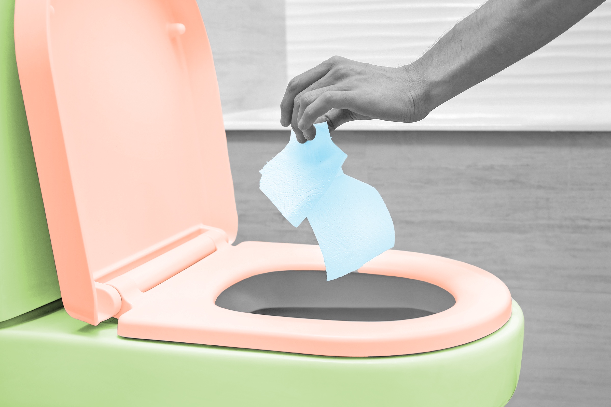 Hand dropping toilet paper into a toilet